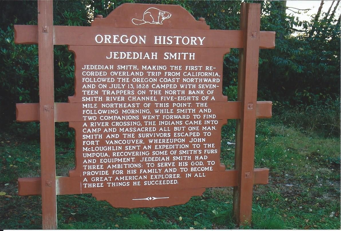 A low stone monument beside a highway, with an inset metal plaque.